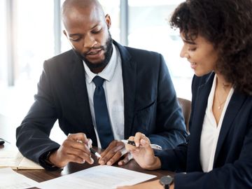 Two professionals reviewing a document together in an office setting.