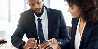 Two professionals discussing documents at a meeting.