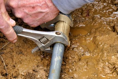 Residential Water Line Repair. A suburban backyard with a trench fixing a broken water pipe.
