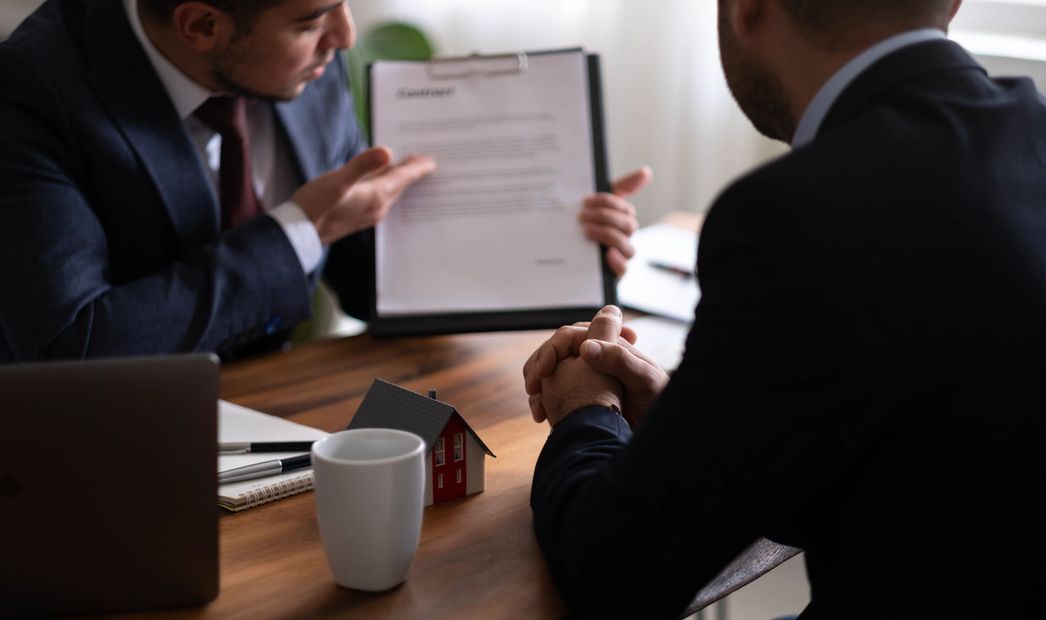 agent working on laptop and writing contract for home purchase