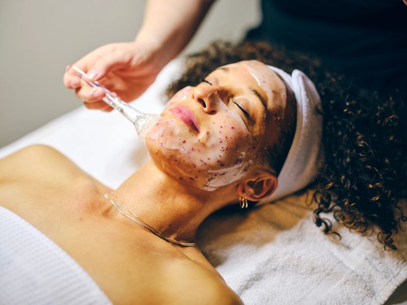 A young woman in a day spa, receiving a facial treatment.
