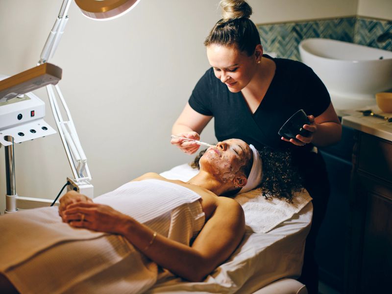 A young woman in a day spa, receiving a facial treatment.