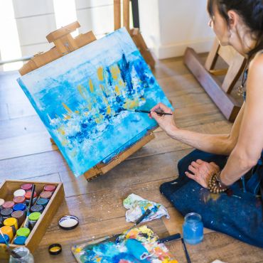 A woman painting a colorful abstract artwork.