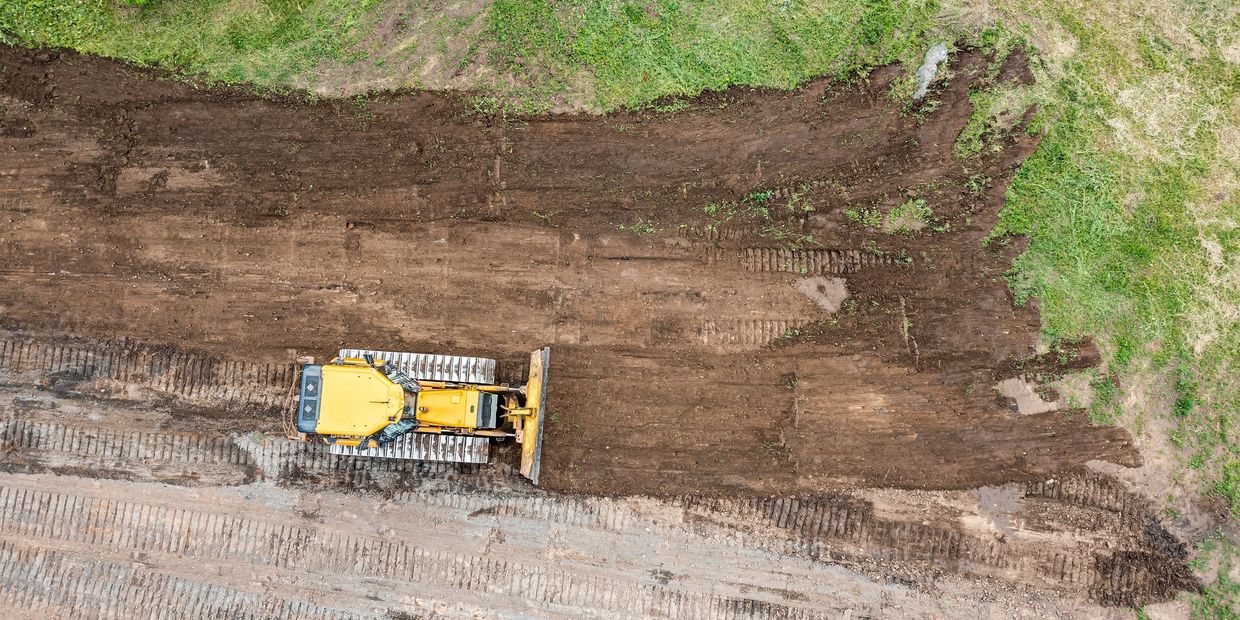 A yellow bulldozer clearing land seen from above.