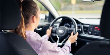 Woman driving a car, focused on the road.