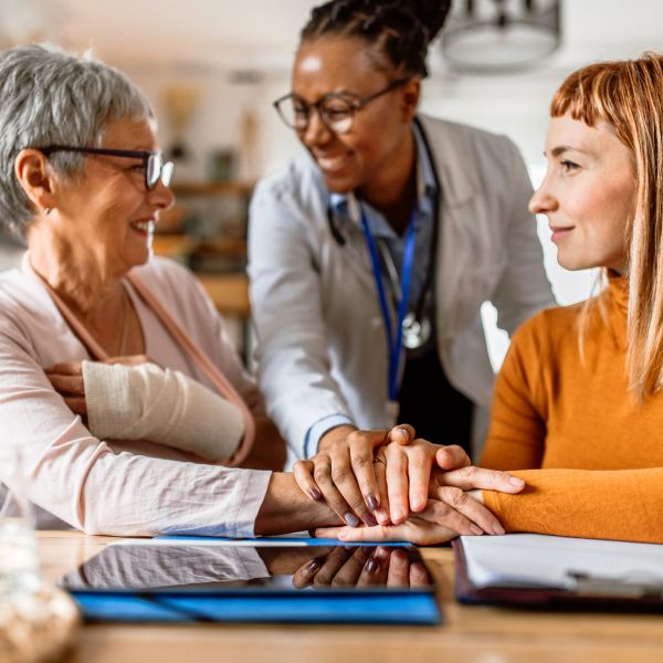 Three women showing support and care, with one wearing a medical cast and a doctor present.