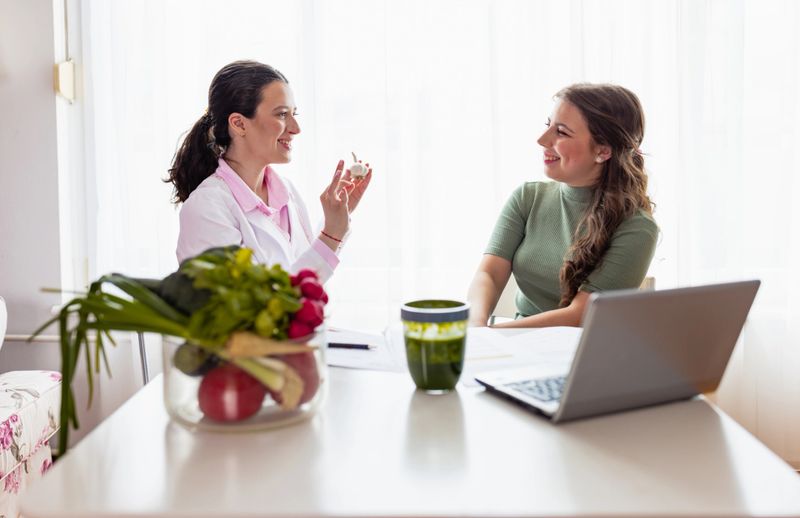 A collaborative and communicative young female nutritionist in lab coat works closely with patients to develop a nutrition plan that meets their unique needs and preferences in her clinic