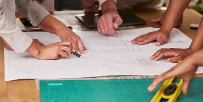 Hands working on architectural blueprints and plans.