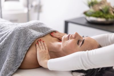 Woman receiving a relaxing neck massage under a gray blanket.