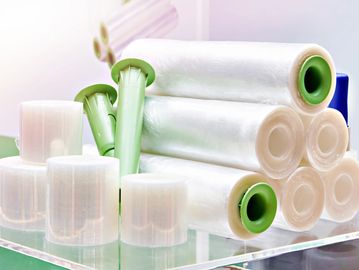 Stacked rolls of transparent stretch film with green plastic cores.