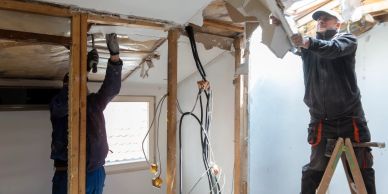 Two men renovating an interior wall.