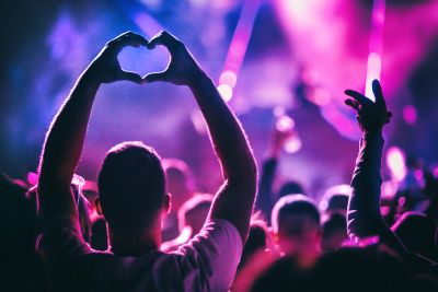 Person forming heart shape with hands at concert.