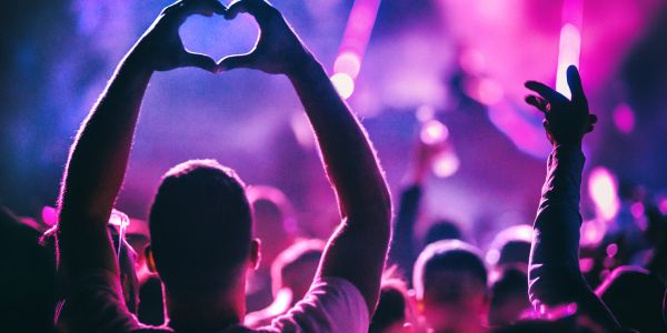 Person making heart shape with hands at a concert.