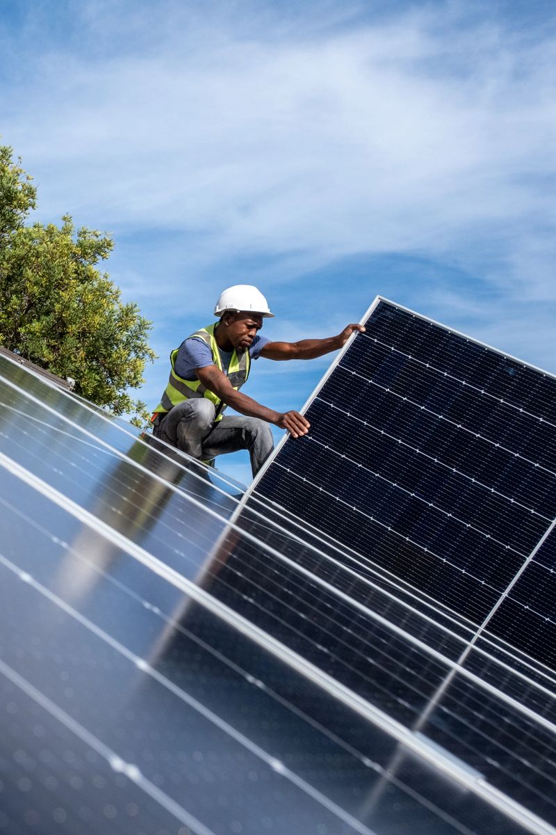 An African Engineer installing solar panels on the roof of a residential house in Cape Town, South Africa. Alternative energy solutions are critical during load shedding in South Africa