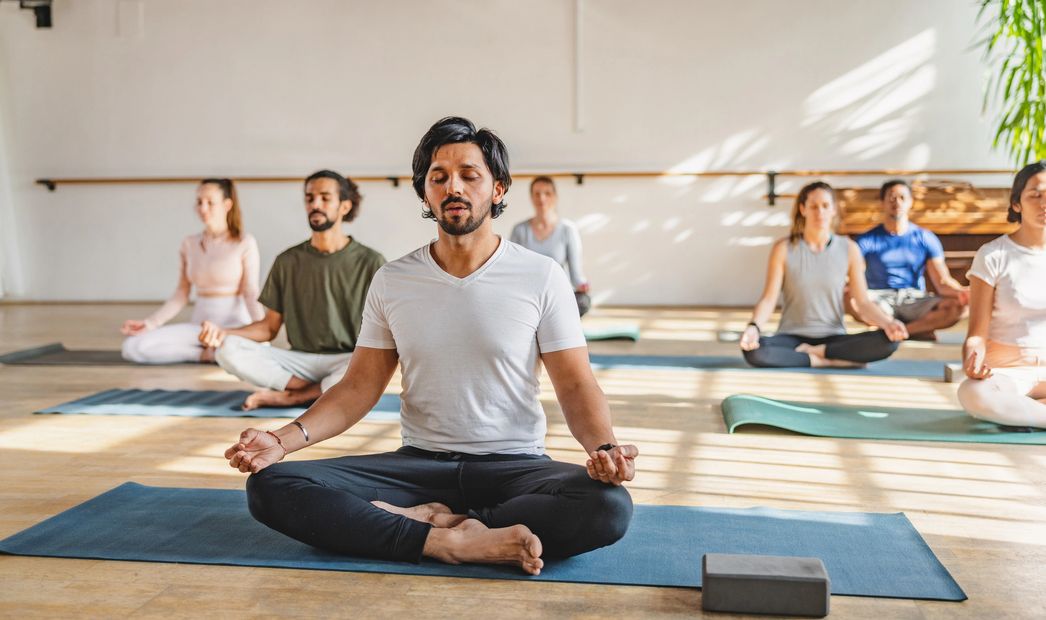 Group of people meditating in a bright yoga studio.