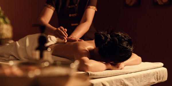 A person receiving a relaxing back massage in a dimly lit room.