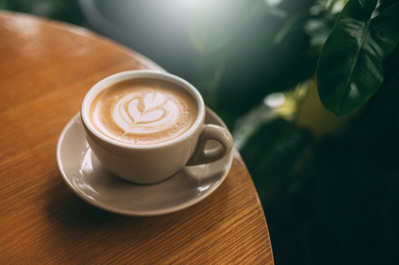 A cup of cappuccino with latte art on a wooden table.