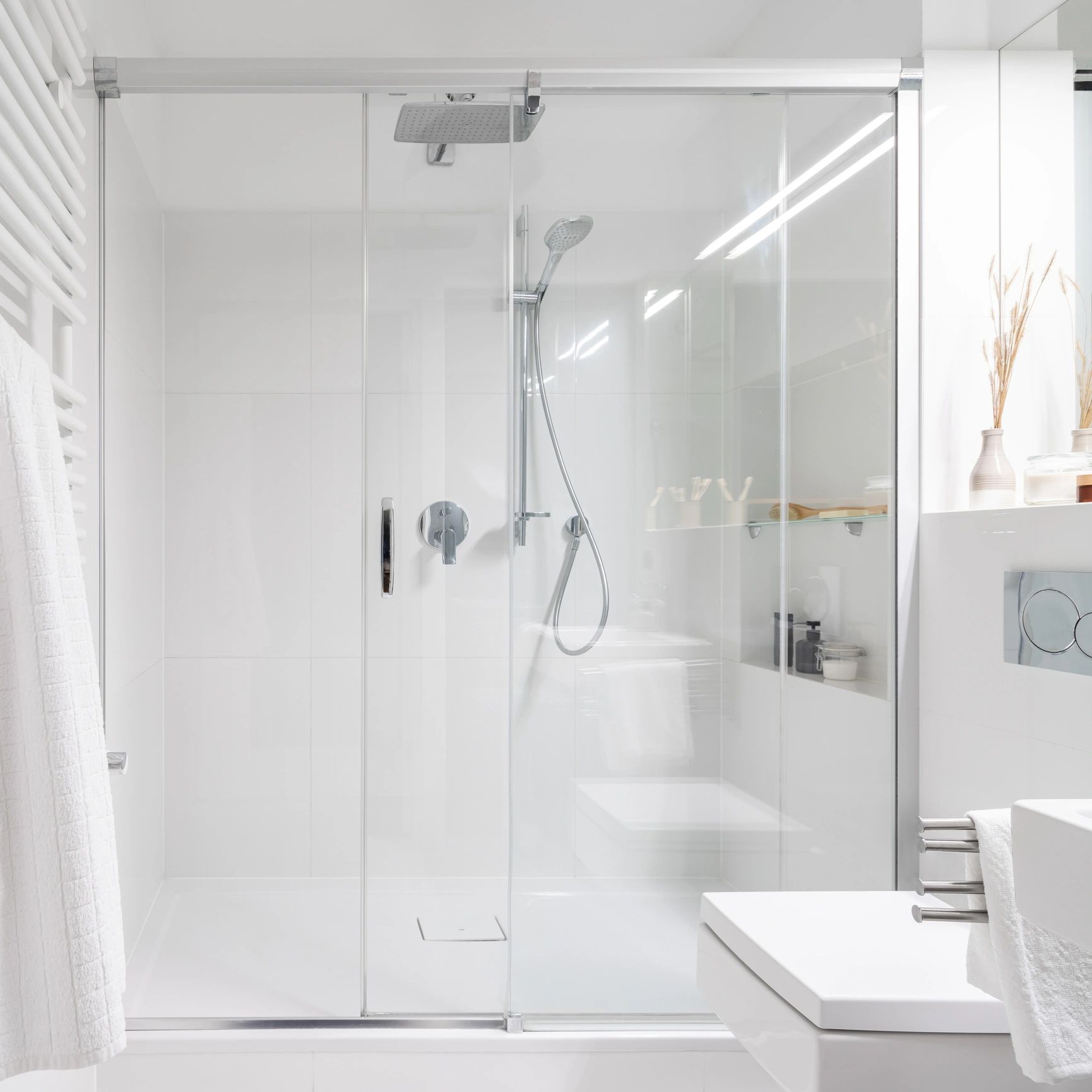 Modern white bathroom with glass shower enclosure.