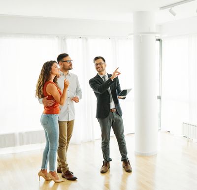Real estate agent showing a couple a bright, empty apartment.