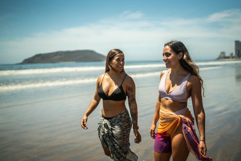 Female traveler friends having a walk by the sea