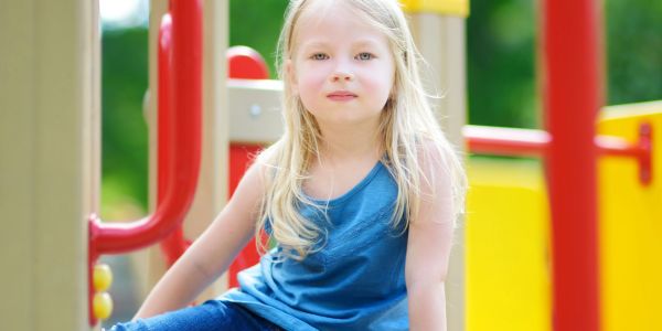 Young girl sitting on playground equipment.