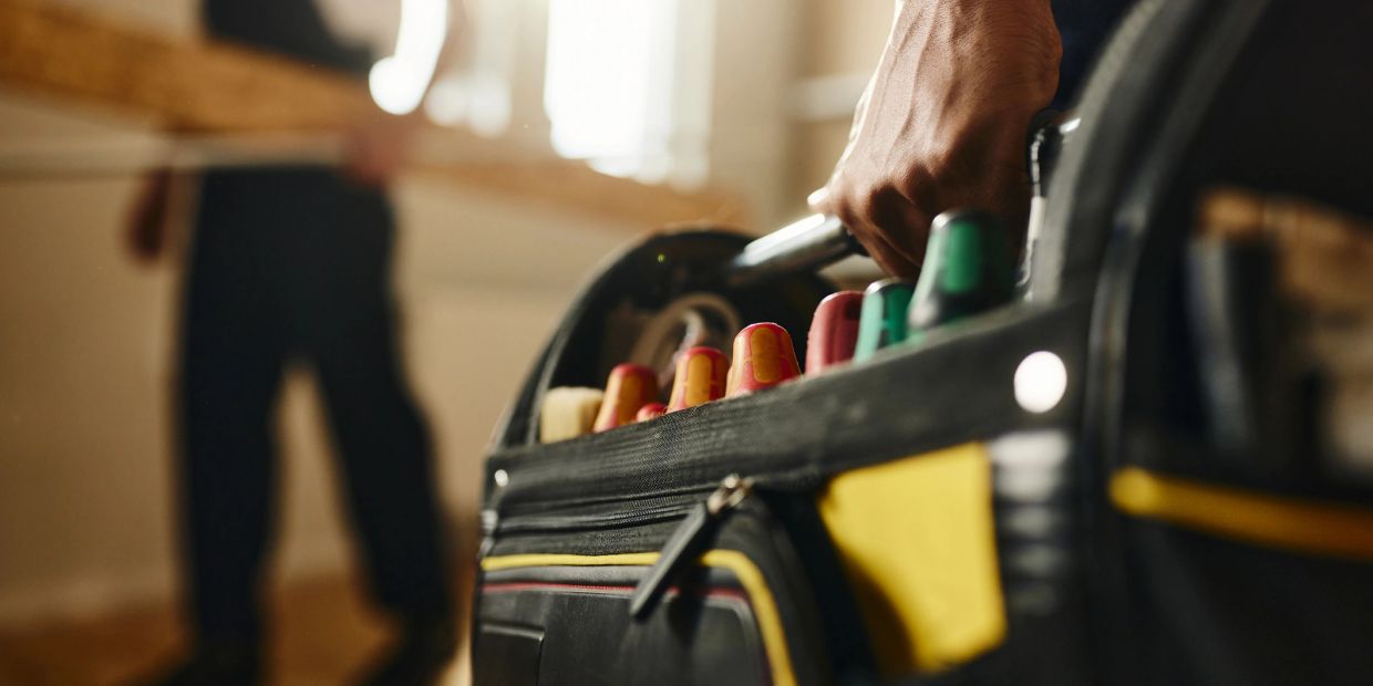 Close-up of a person carrying a toolbox.