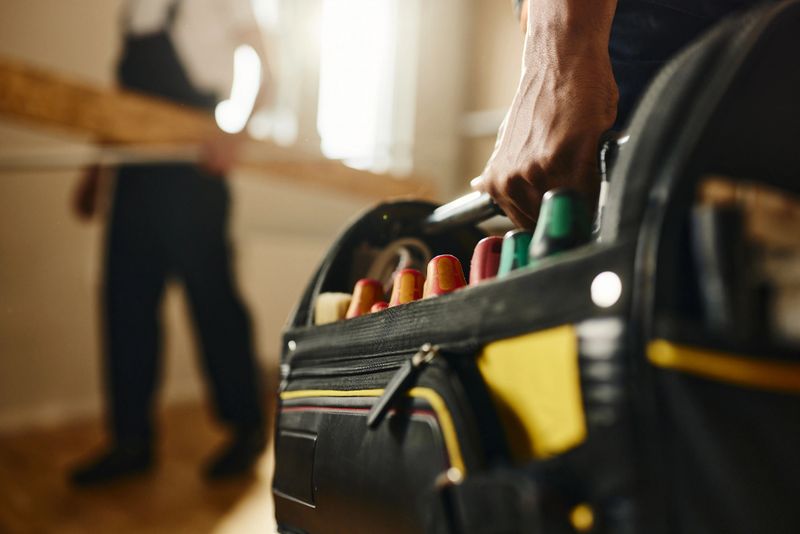 Close up of unrecognizable worker carrying toolbox in the apartment.