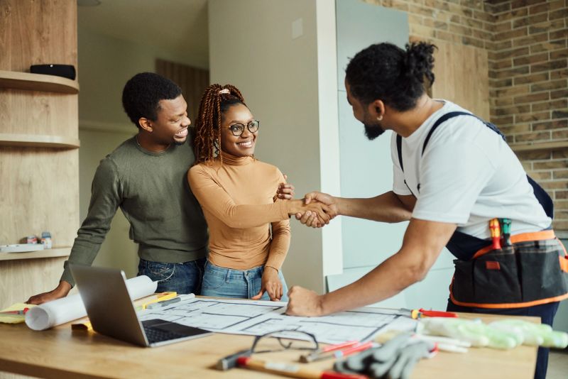 Happy African American couple came to a successful deal with manual worker at moving house.