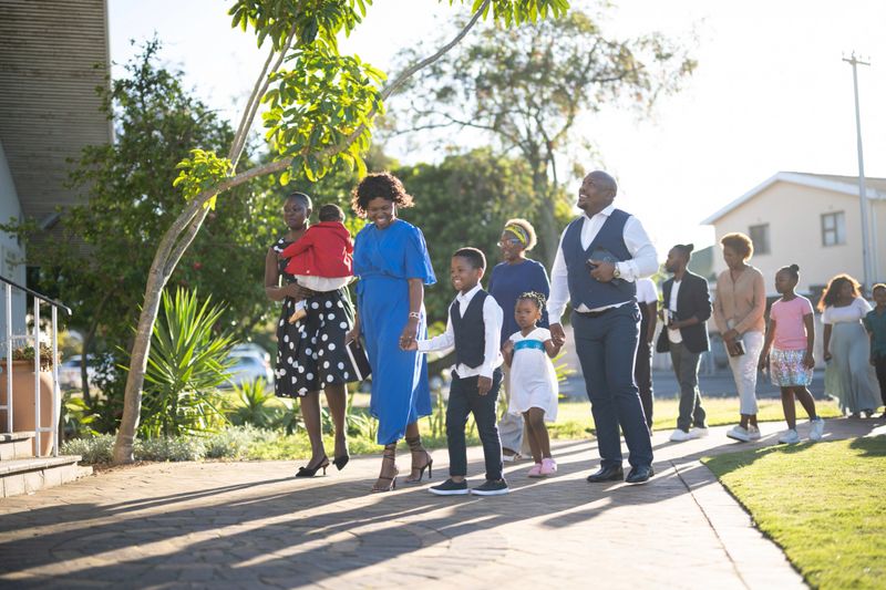 A large happy multi-generational family all walking together up the pathway towards church in the morning