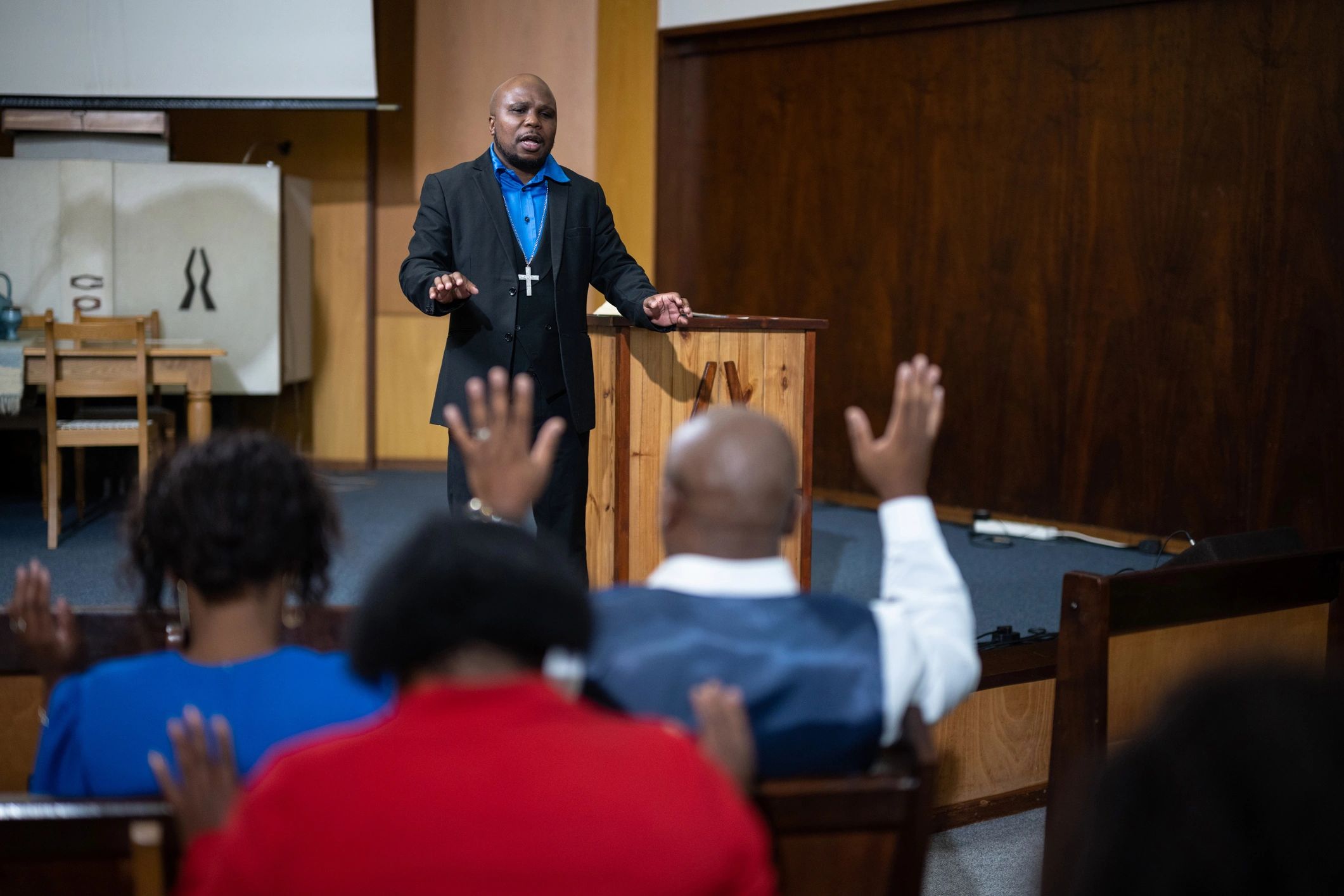 Man preaching to a church congregation with raised hands.
