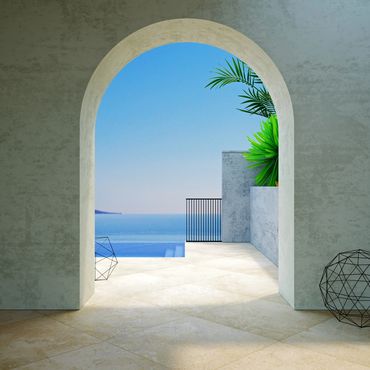 Archway view of a serene pool and ocean under a clear sky.