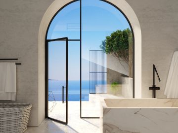 Modern bathroom with arched glass door opening to ocean view.