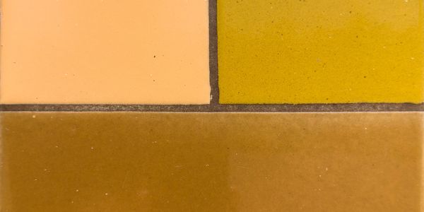 Close-up of three rectangular tiles in peach, yellow, and brown colors.