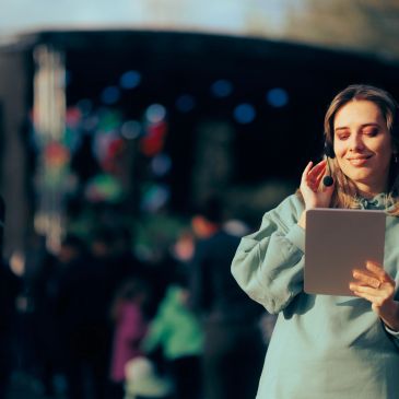 Young woman enjoying music on a tablet outdoors.