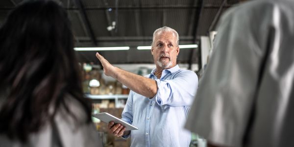 Man explaining something to two people using a tablet.