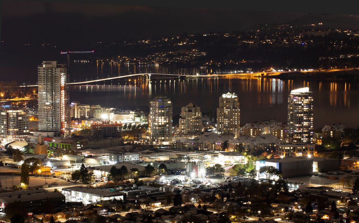 Night cityscape with illuminated buildings and a bridge over water.