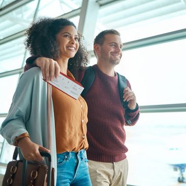 Happy couple with luggage and boarding passes at the airport.