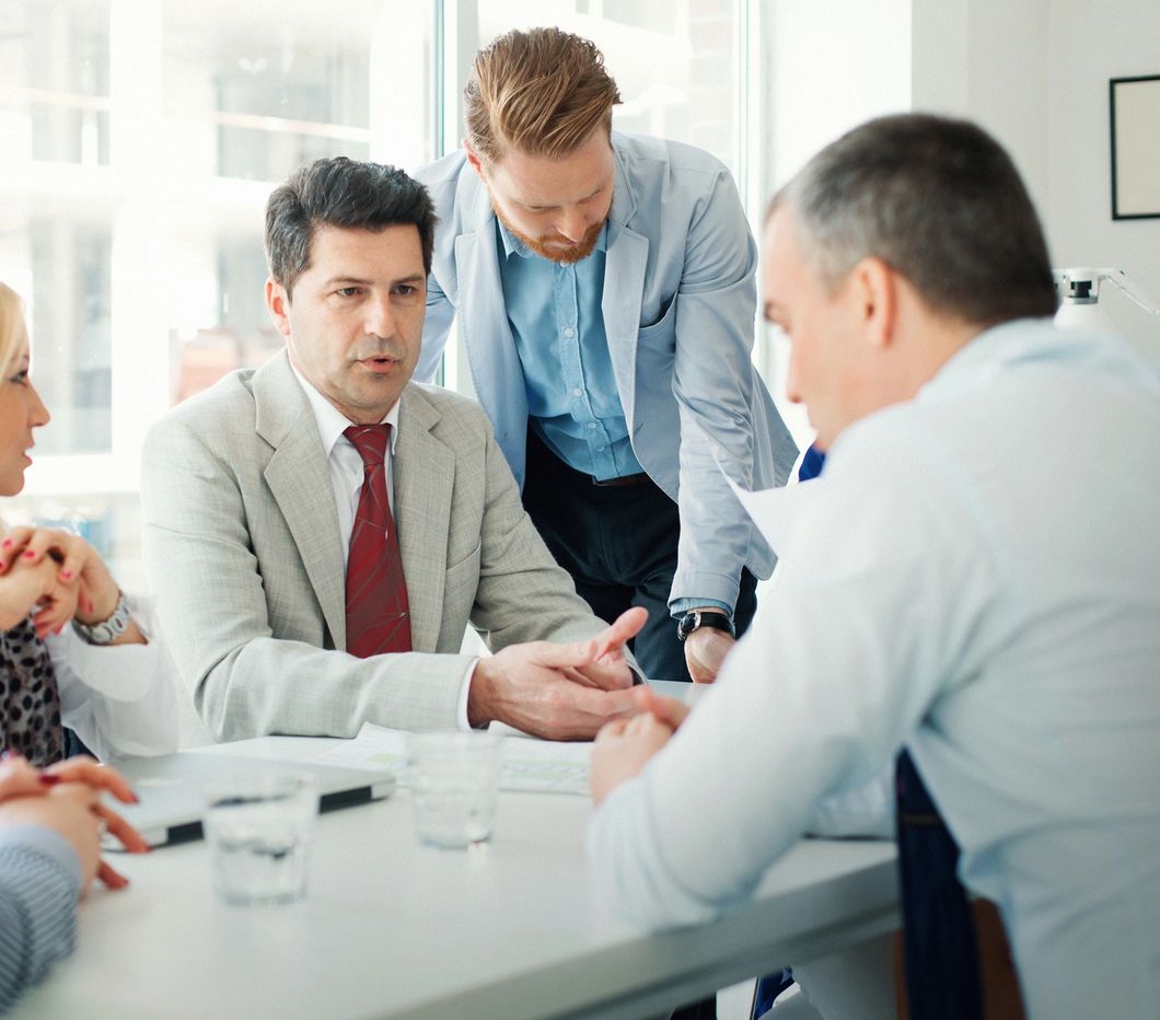 Business professionals engaged in a serious discussion around a conference table.