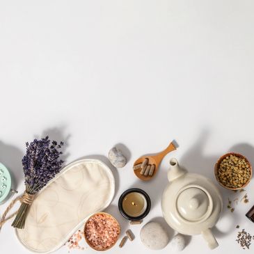 Flat lay of wellness items including a teapot, lavender, salt, and capsules on a white background.