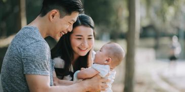 Happy parents holding their baby outdoors.