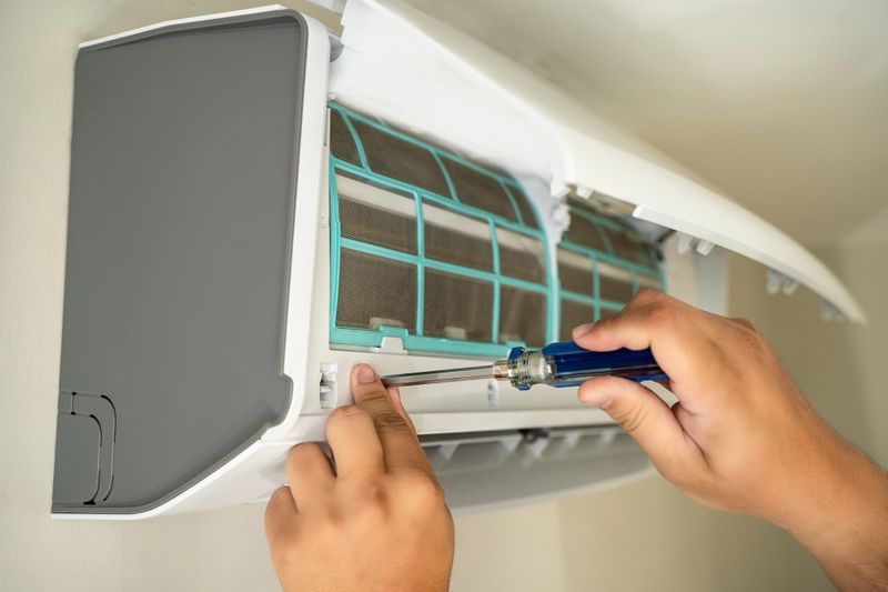 Male professional technician fixing An electrician repairs an air conditioner indoors. removing air filter repairing hot temperatures