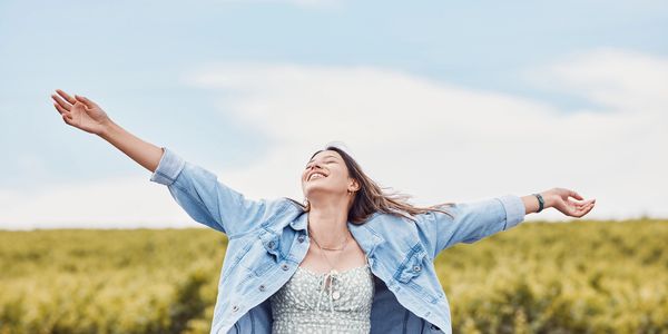 girl standing and celebrating in front of a field 