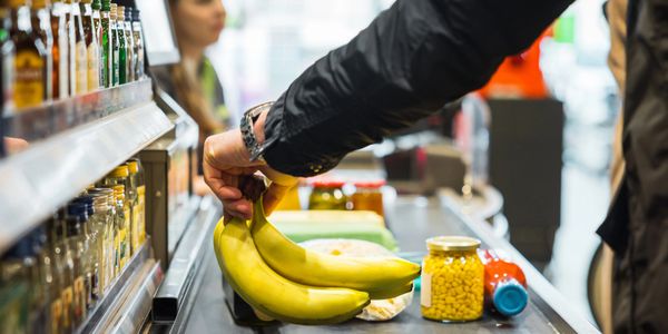 A person placing bananas on a grocery checkout conveyor belt.