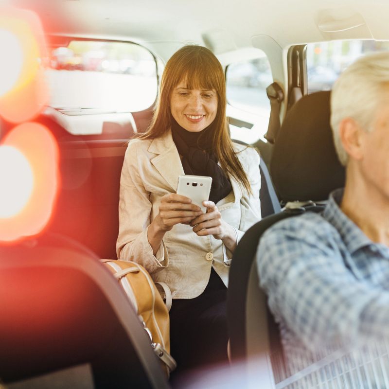 Mature businesswoman using smartphone during a taxi ride