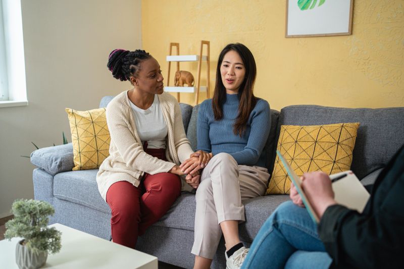 Multiracial lesbian couple having a couple therapy, led by the female Caucasian psychotherapist