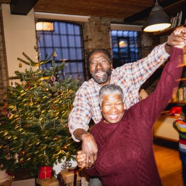 Happy couple dancing by a Christmas tree.