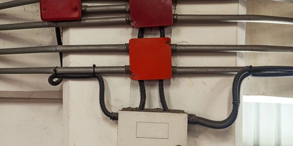 Electrical junction boxes and conduits mounted on a wall in an industrial setting.