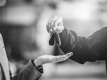 Person handing over car keys to another person.