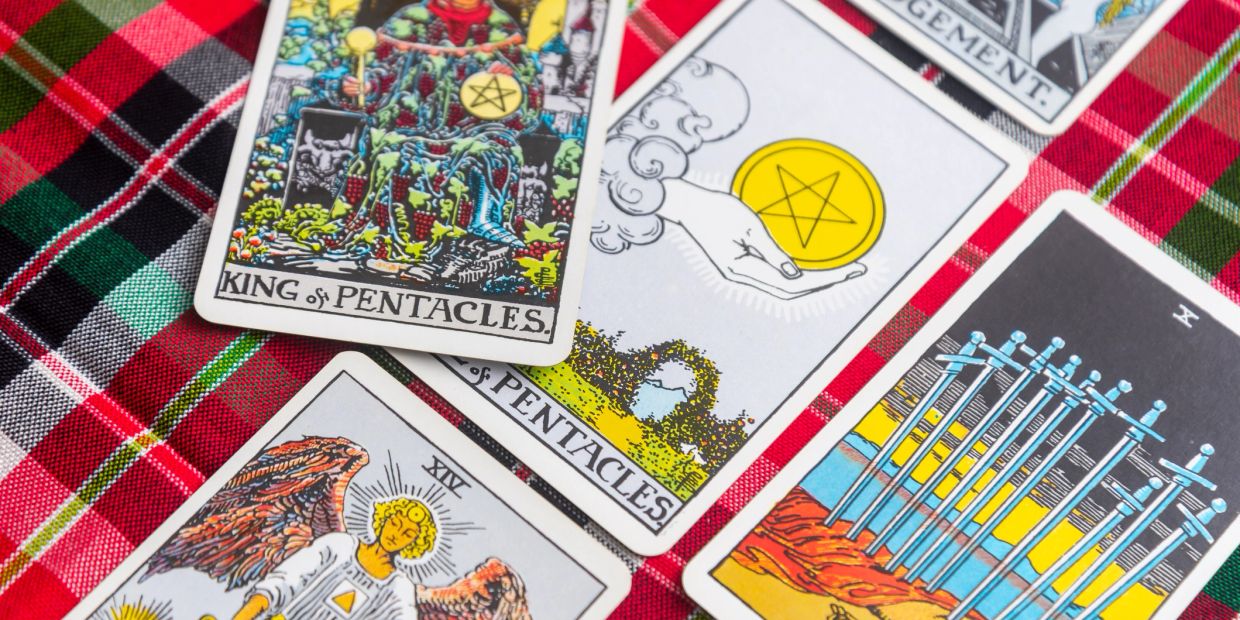 Tarot cards are scattered on a plaid surface.