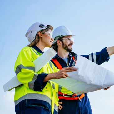 Two construction workers reviewing a blueprint outdoors.